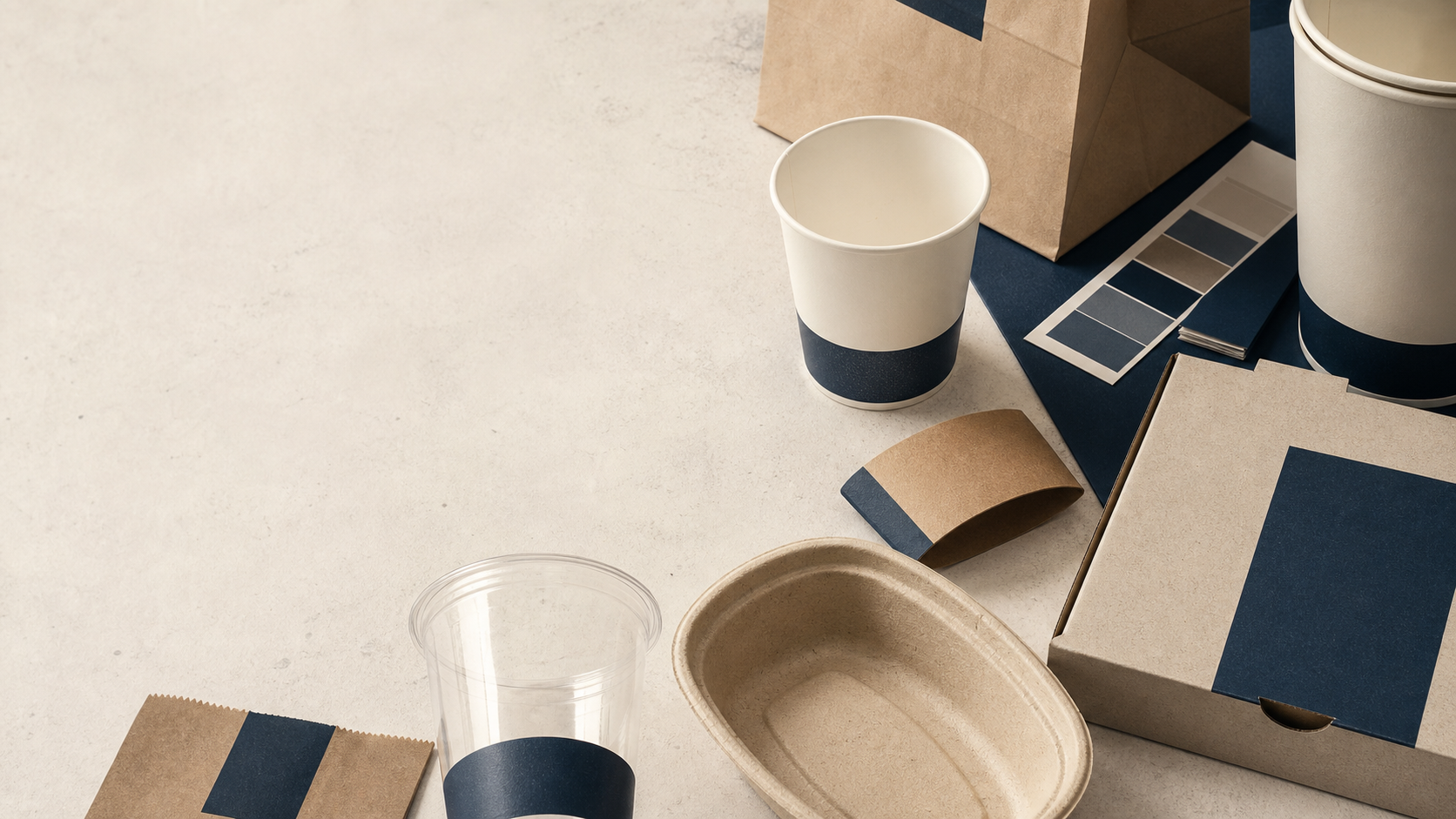 Foodservice packaging samples, paper cups, bags, boxes and material swatches on a worktable
